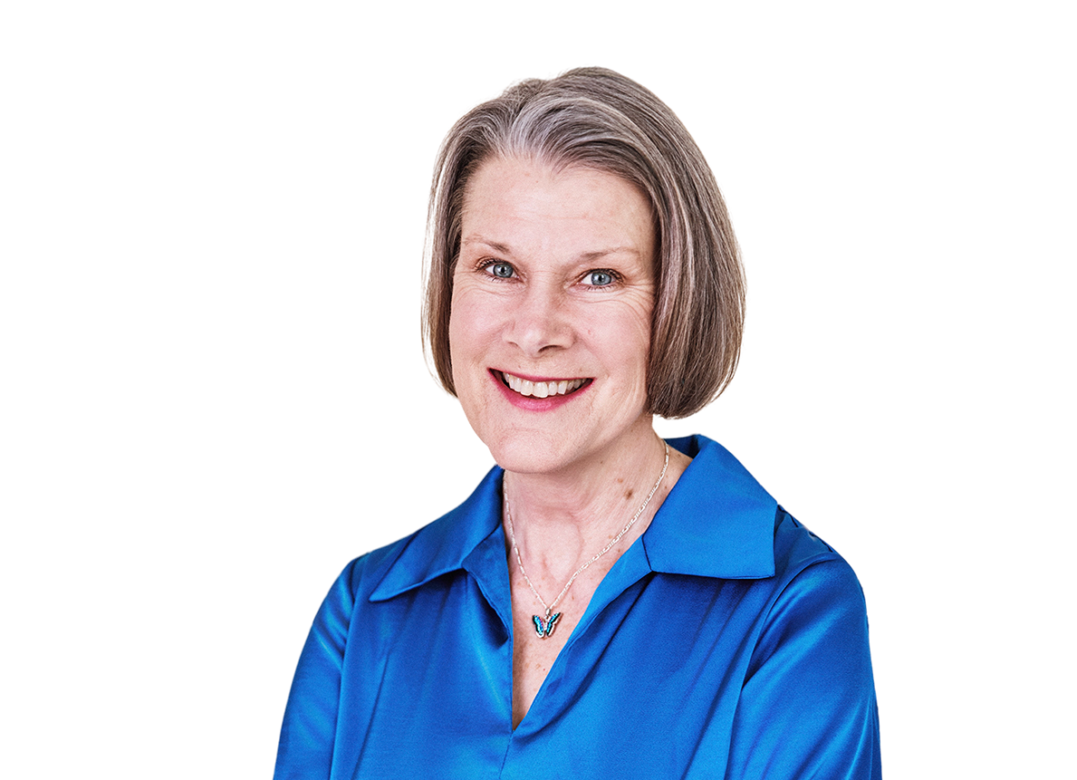 Smiling woman with short gray hair wearing a royal blue blouse and butterfly necklace.
