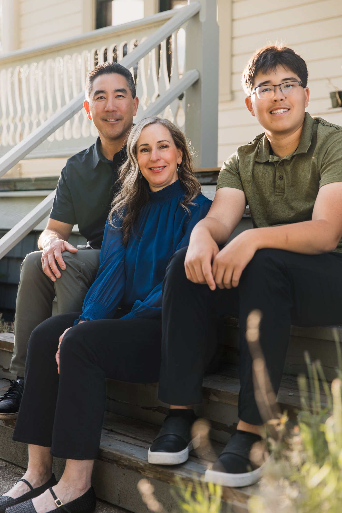 Family smiling, sitting on the steps of historic London Farm, Richmond, BC at sunset.