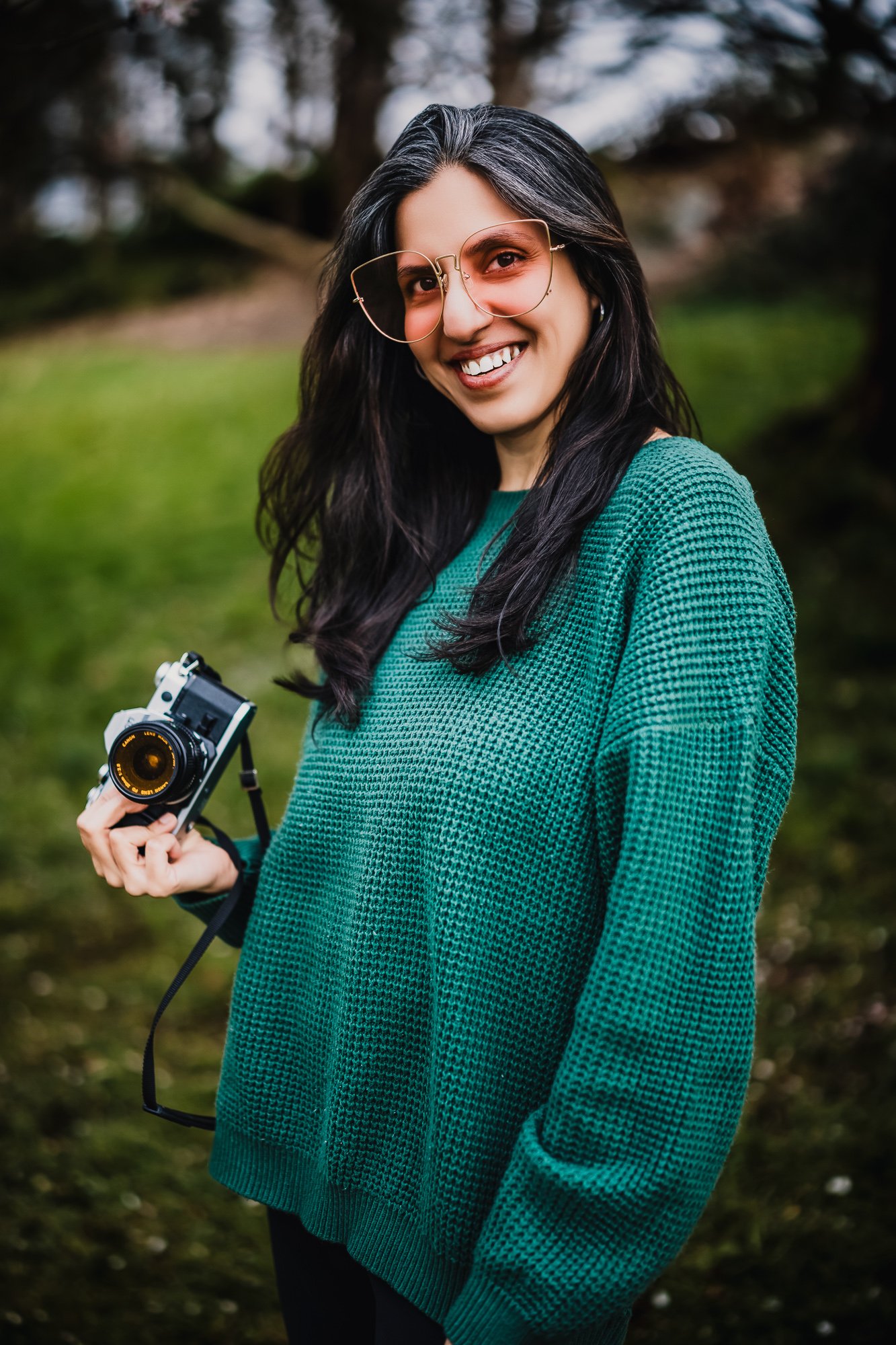 A woman holding a camera, smiling for vancouver branding picture.