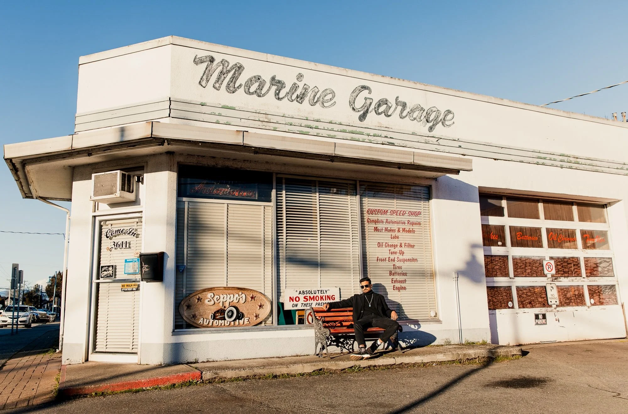 Young man sitting in front of Seppo's Auto in historic Steveston Village, Richmond, BC.