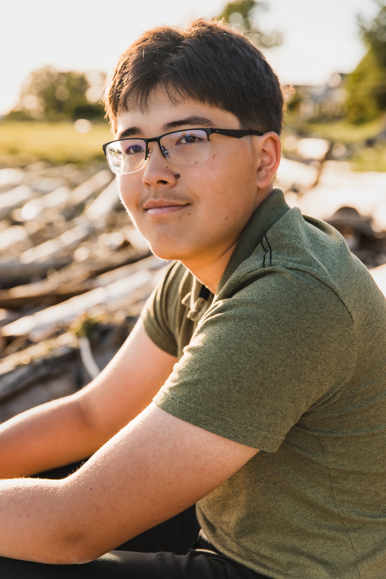 Young man sitting on log at sunset at Gilbert Beach, Richmond, BC.