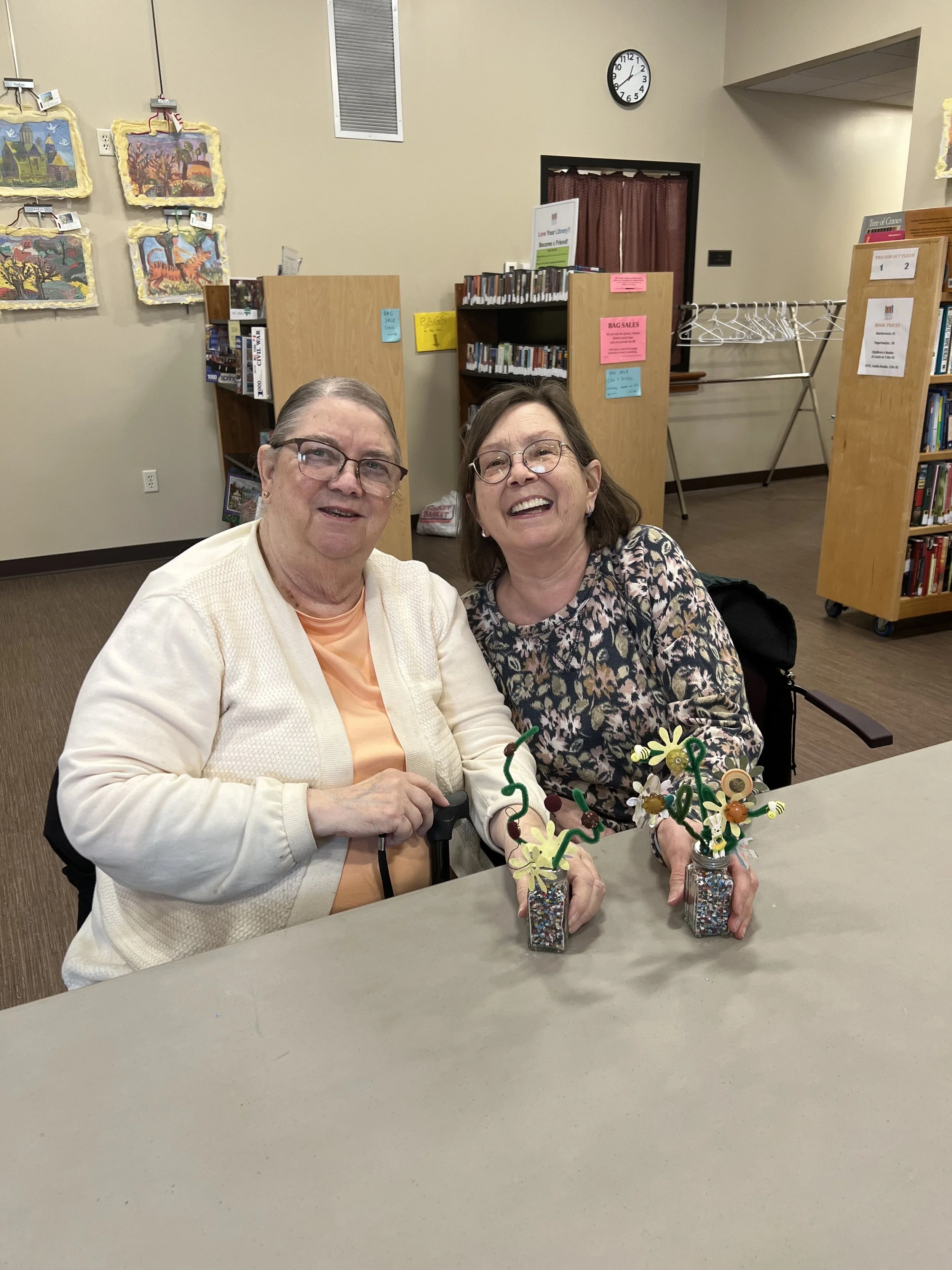 Two women smiling and showing off their crafts