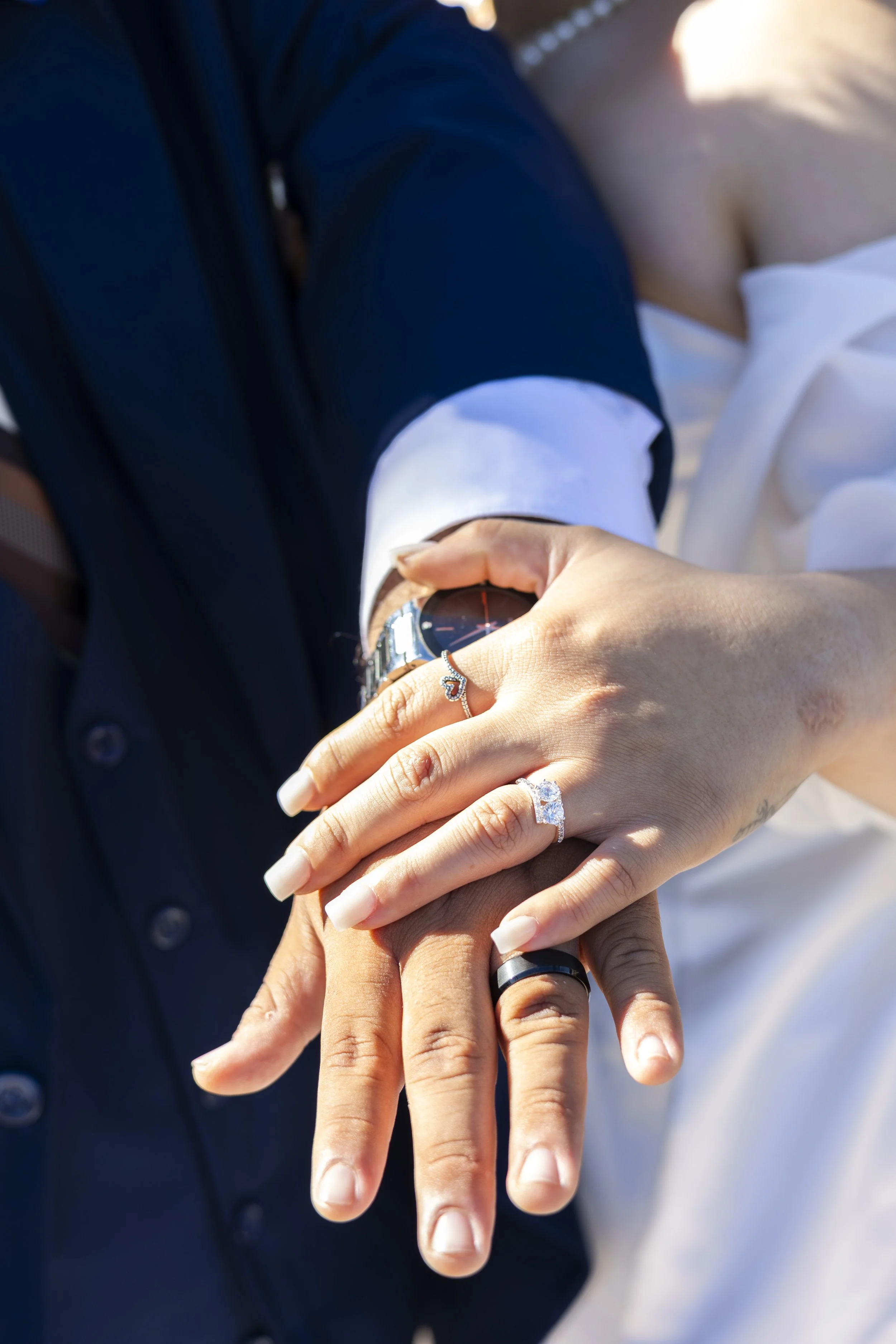 Close-up of a couple holding hands, with wedding rings visible, emphasizing their union and commitment.