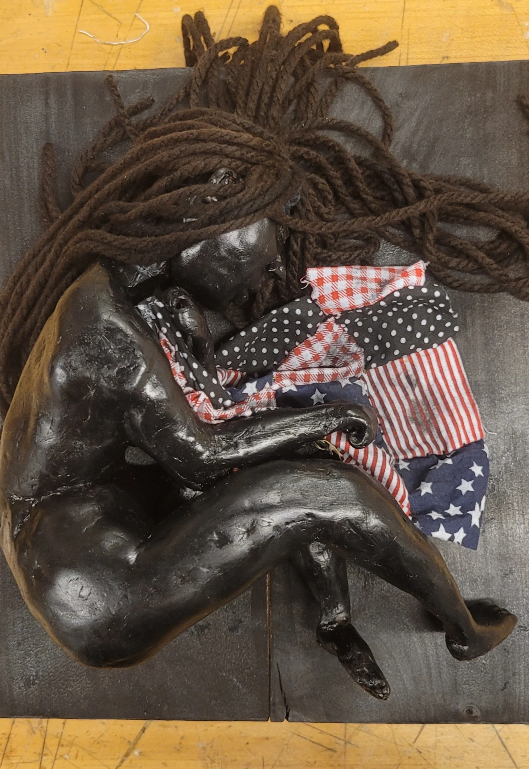 holding on while i'm able. 2025, polymer clay, brown yarn, charred wood, fabric. 