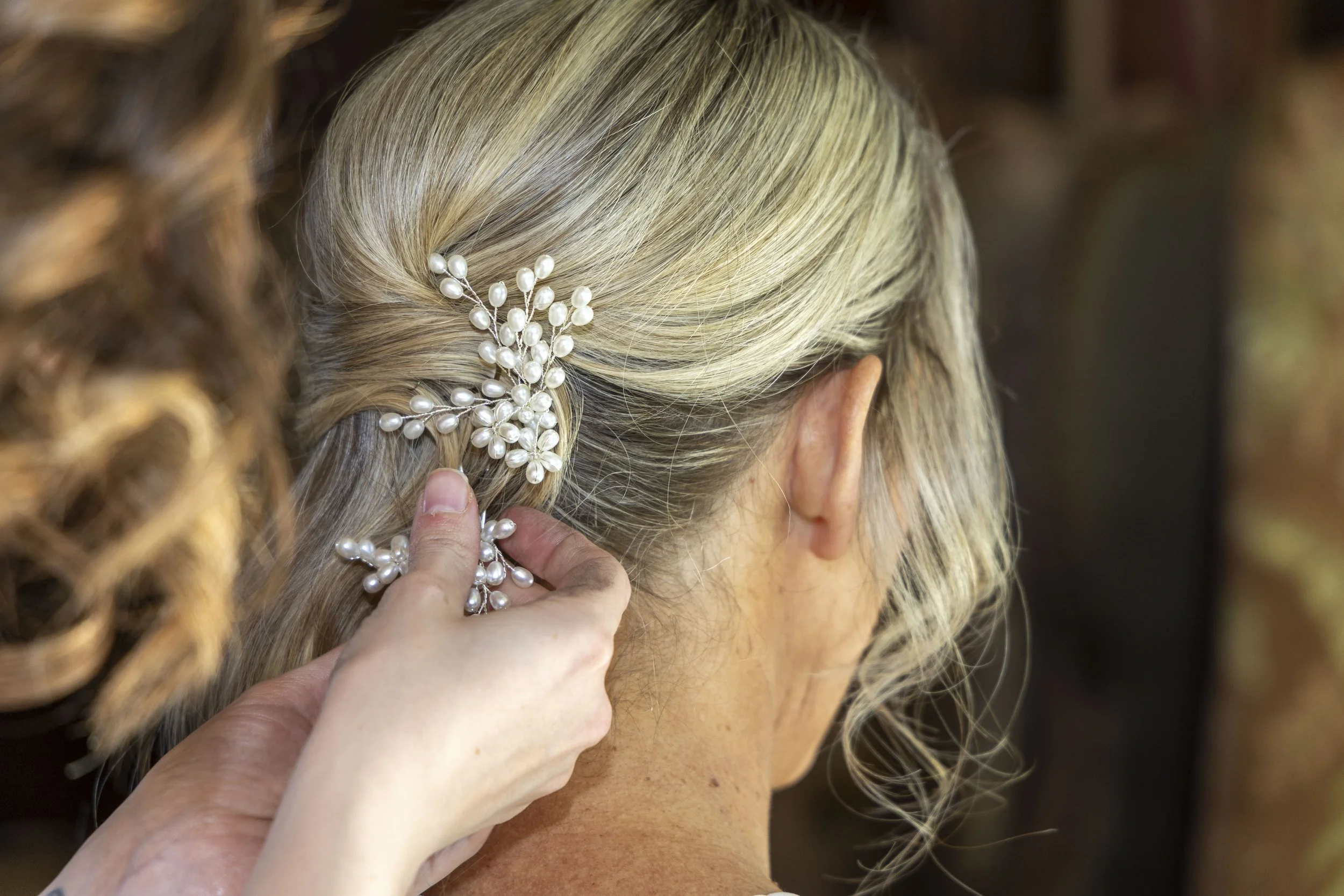 Pearl hair accessory being placed in blonde hair by wedding hairdresser Hawkes Bay