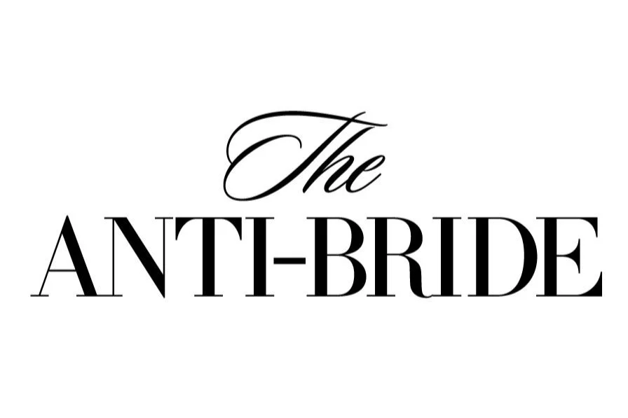 Text reading 'The Anti-Bride' in black on a clean white background — 'The' appears in a delicate cursive font above 'Anti-Bride' in bold serif. The Anti-Bride is a modern wedding platform celebrating nontraditional aesthetics, intentional design.