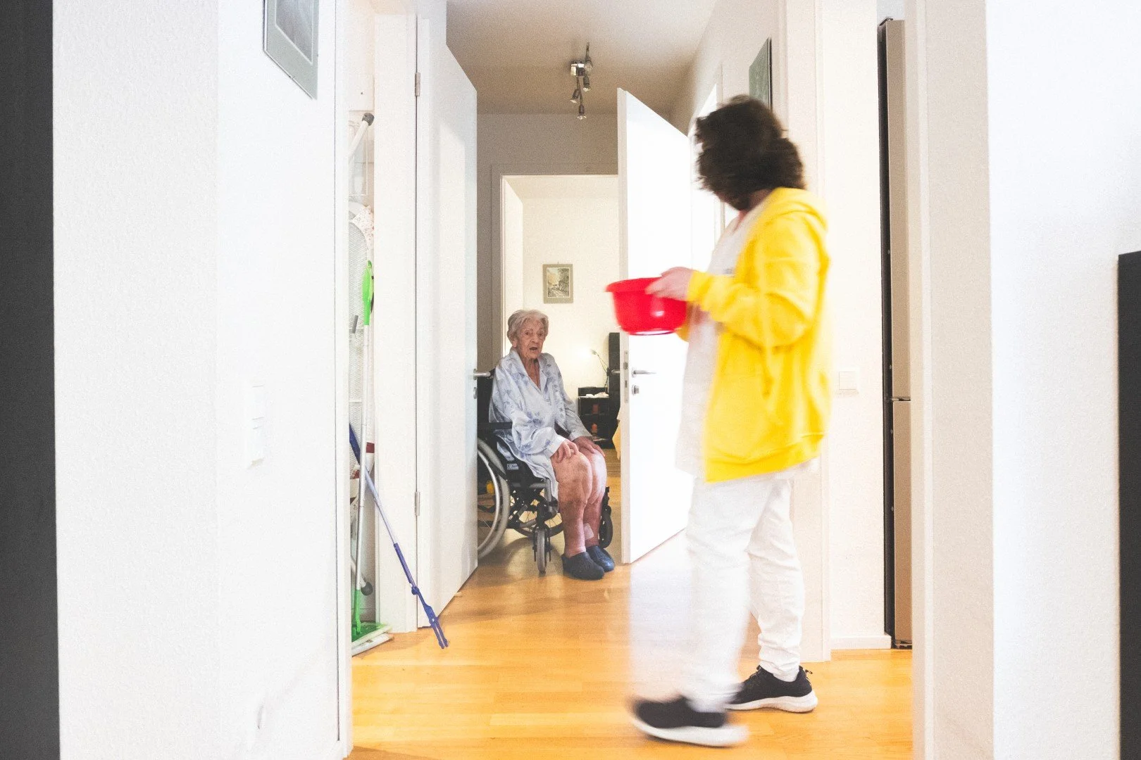 Pflegekraft bringt einer älteren Frau im Rollstuhl in einer Wohnung Essen