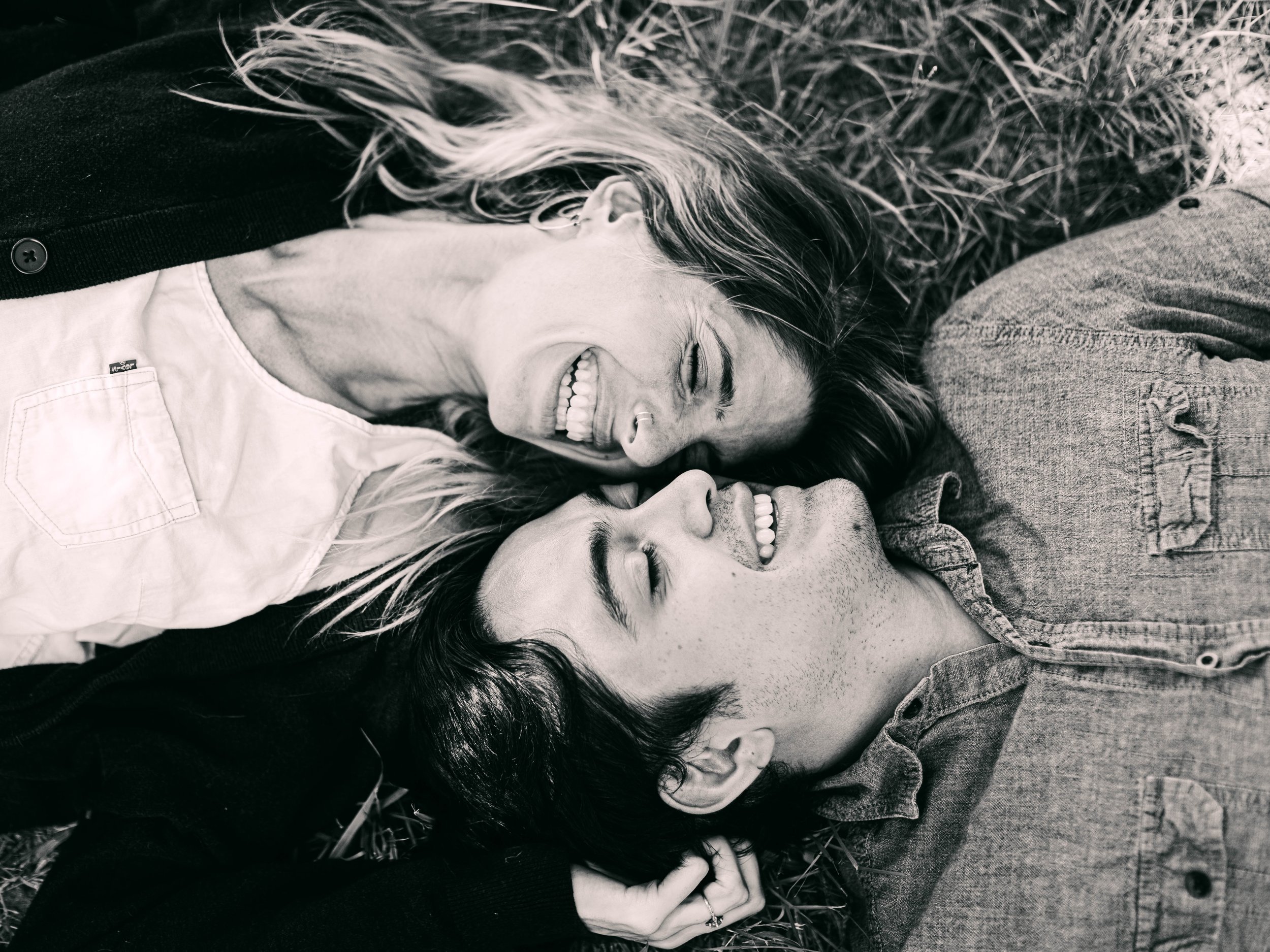 Couple lying close together, relaxed and laughing, sharing a connected moment during couples immersive therapy