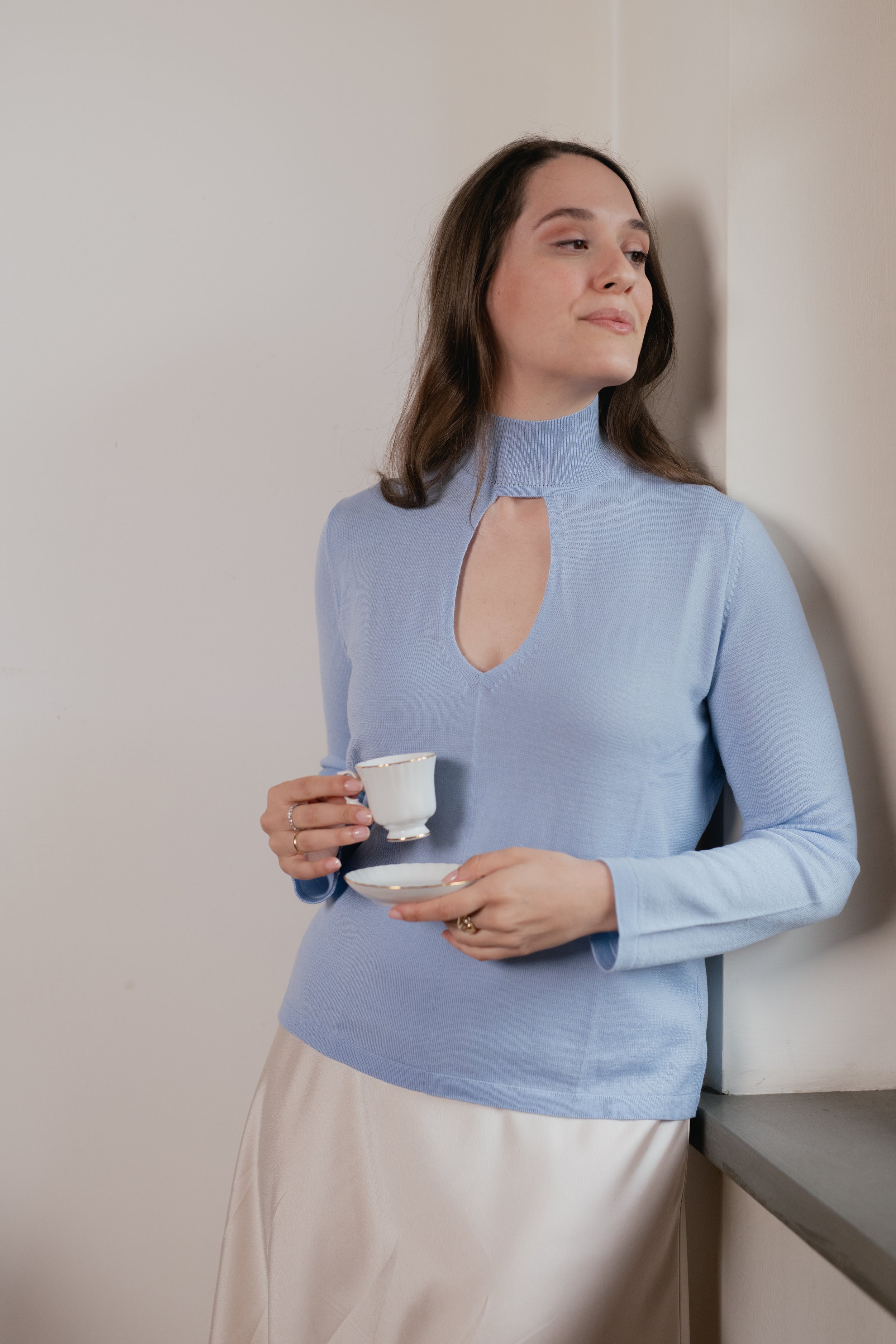 Donna con maglione azzurro e tazza di tè.