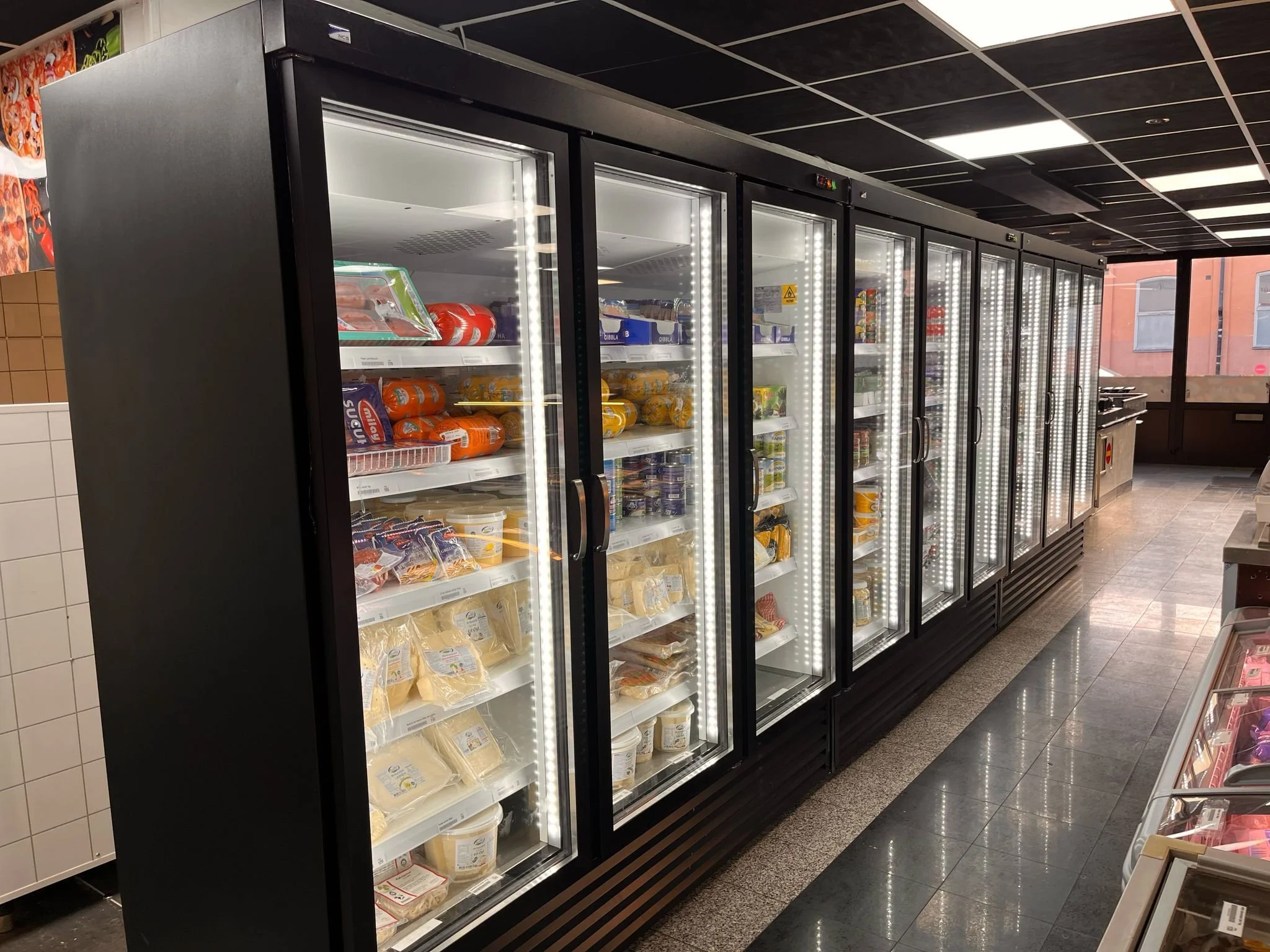 Displaykylar med glasdörrar installerade i livsmedelsbutik för energieffektiv exponering av kylvaror.