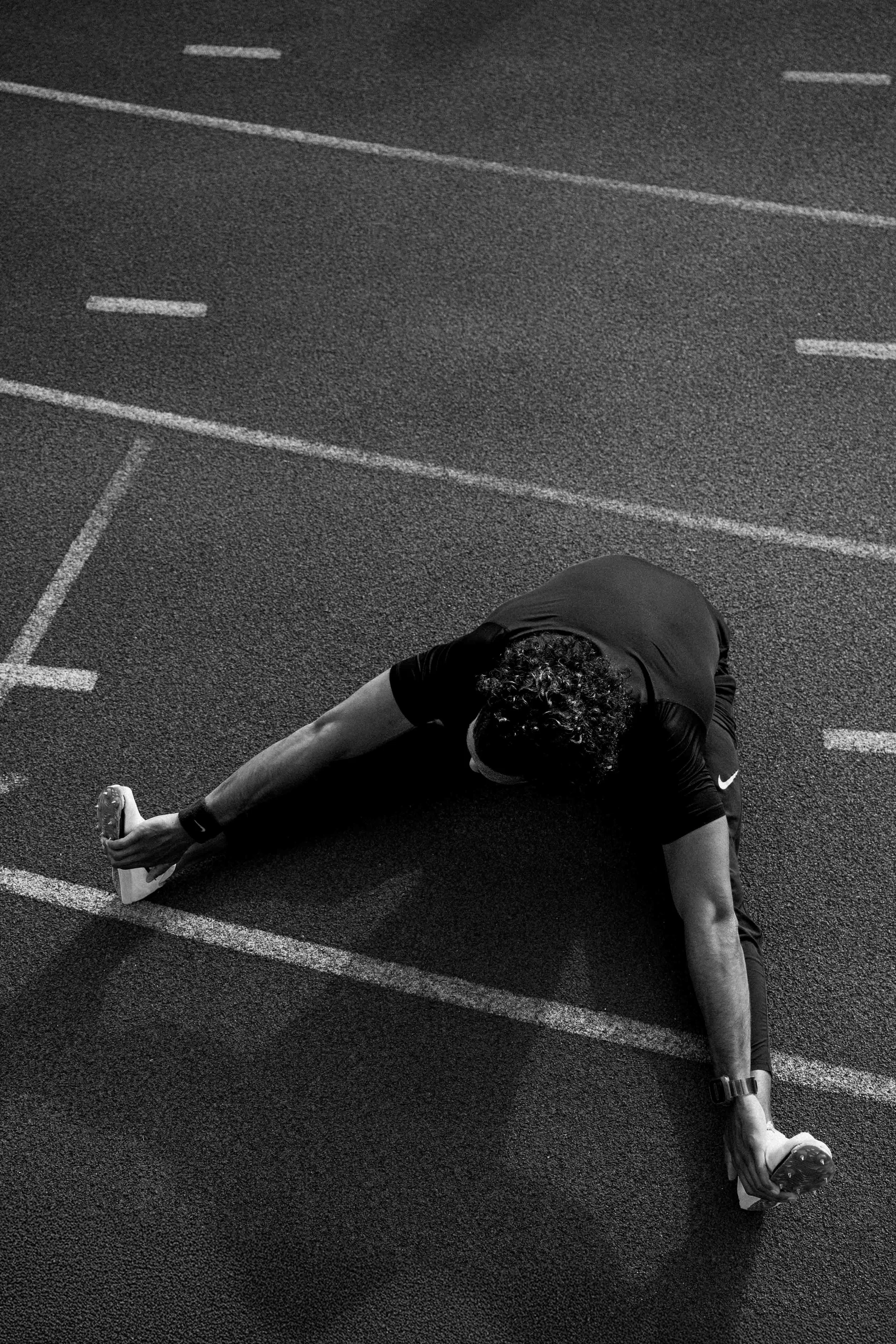 Une personne faisant un étirement d'une jambe sur une piste d'athlétisme. Issue d'une vidéo de sport du Studio Kroma pour le projet Limitless.