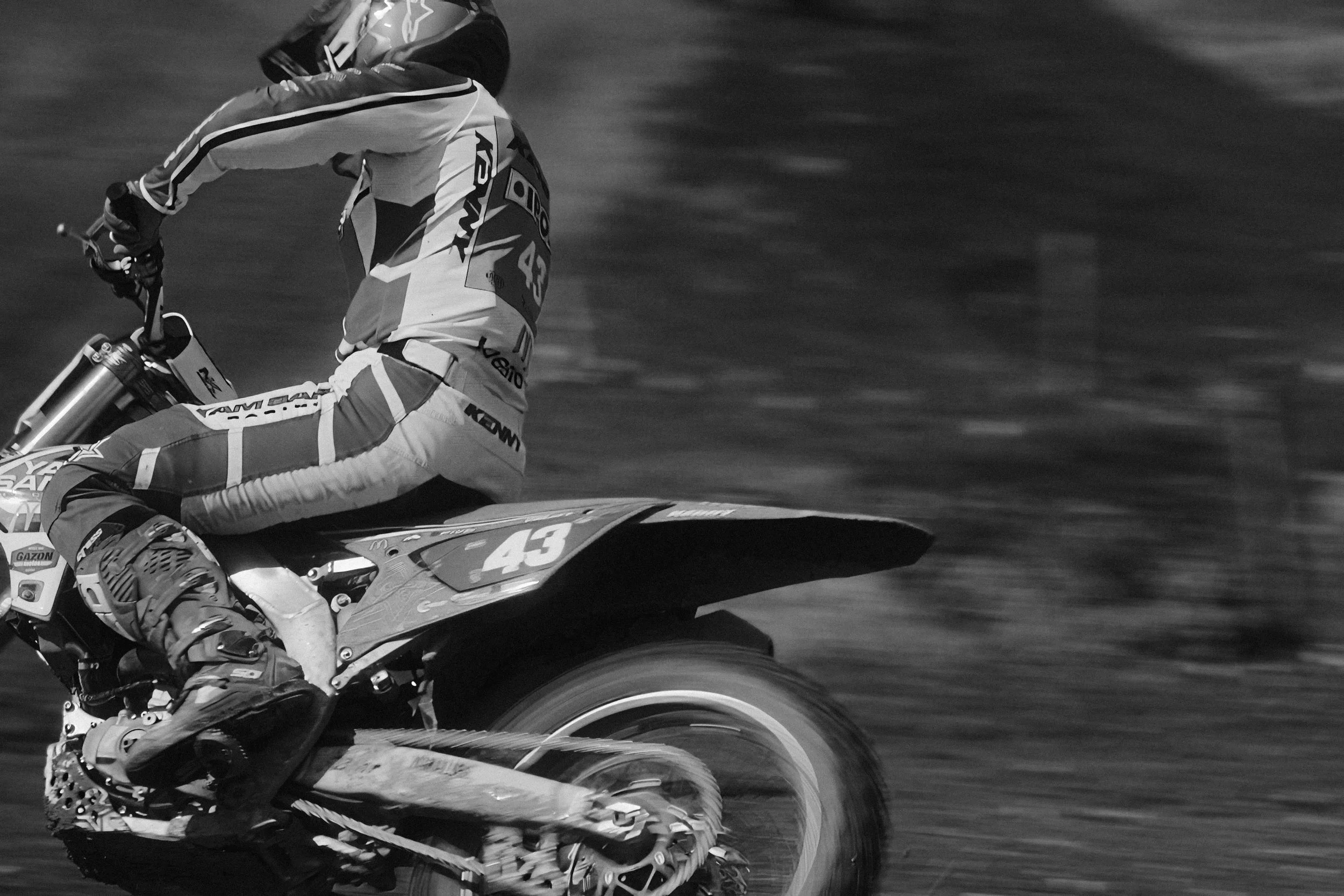 Un motard en pleine course, vêtu d'une combinaison de pilotage et d'un casque, roulant sur une moto tout-terrain, avec le numéro 43 affiché, dans un environnement flou indiquant la vitesse. Issue d'une vidéo de sport du Studio Kroma pour le projet Li