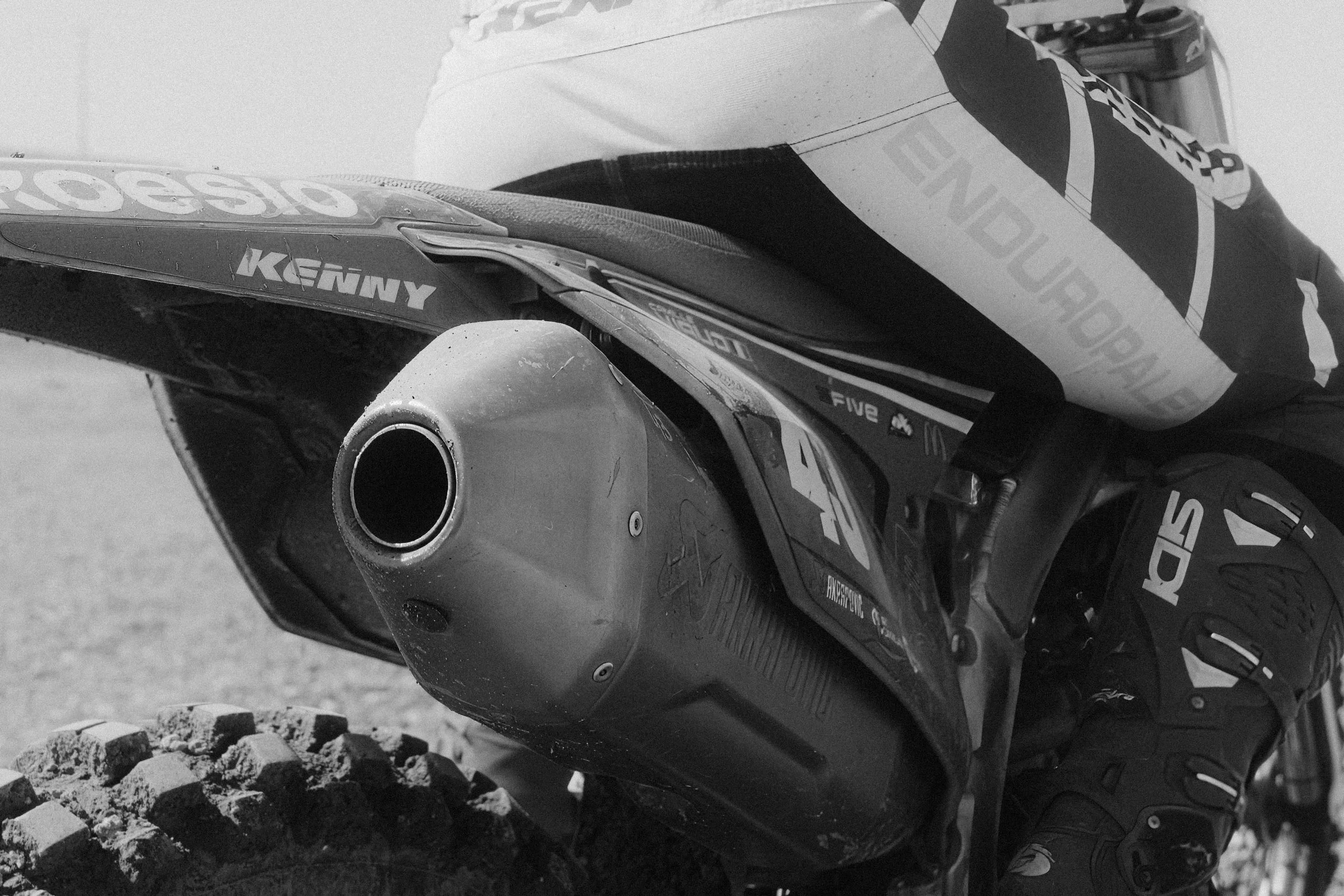 Photo en noir et blanc d'une moto tout-terrain avec un silencieux visible, des chaussures de motocross. Issue d'une vidéo de sport du Studio Kroma pour le projet Limitless.