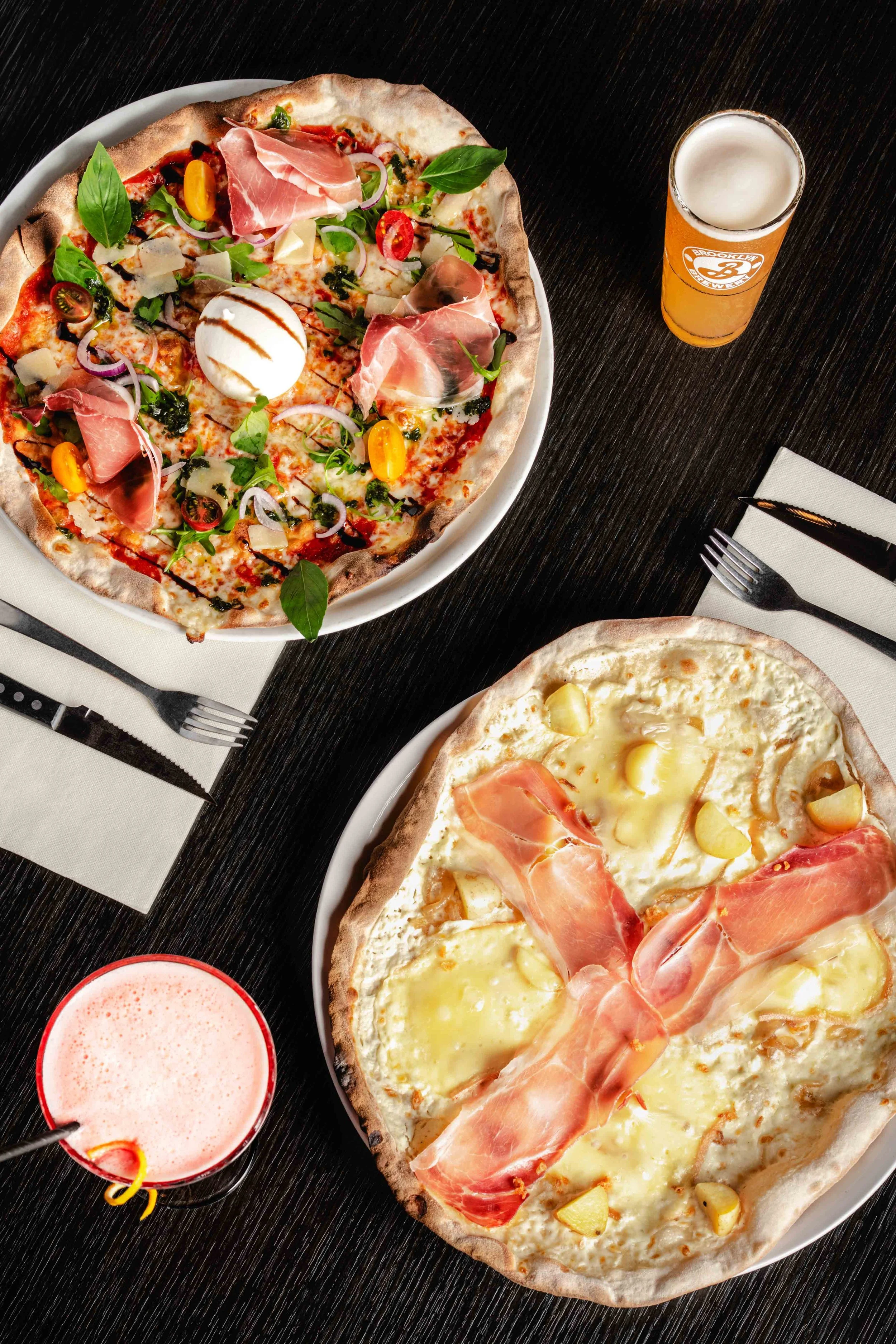 Deux pizzas accompagnées d'une bière et d'une boisson rose mousseuse. Issue d'un projet de photo culinaire du Studio Kroma pour le restaurant L'Eden Bowl.