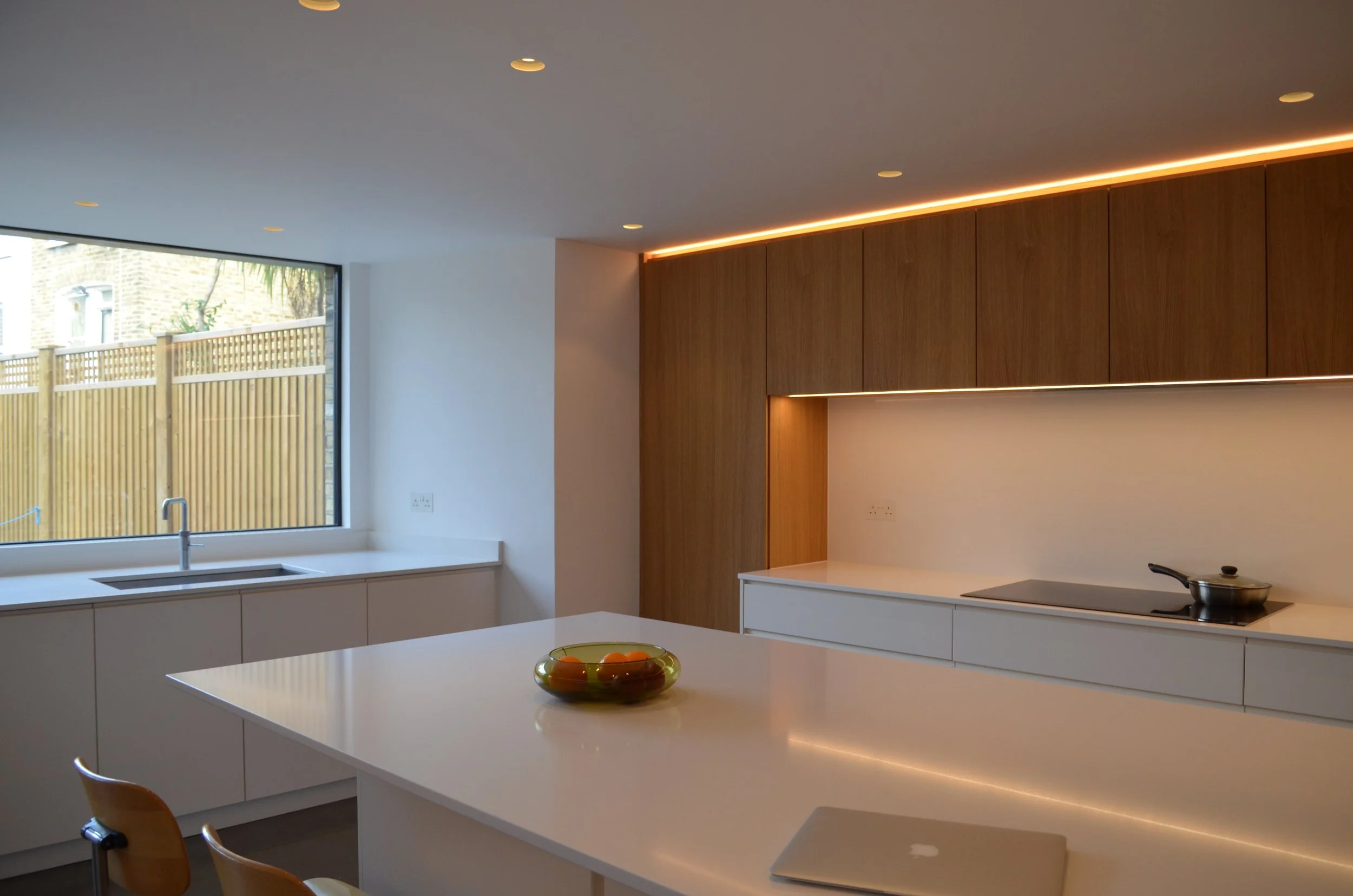 Bespoke kitchen with white countertops, wooden cabinets, a large window, and a large central island.