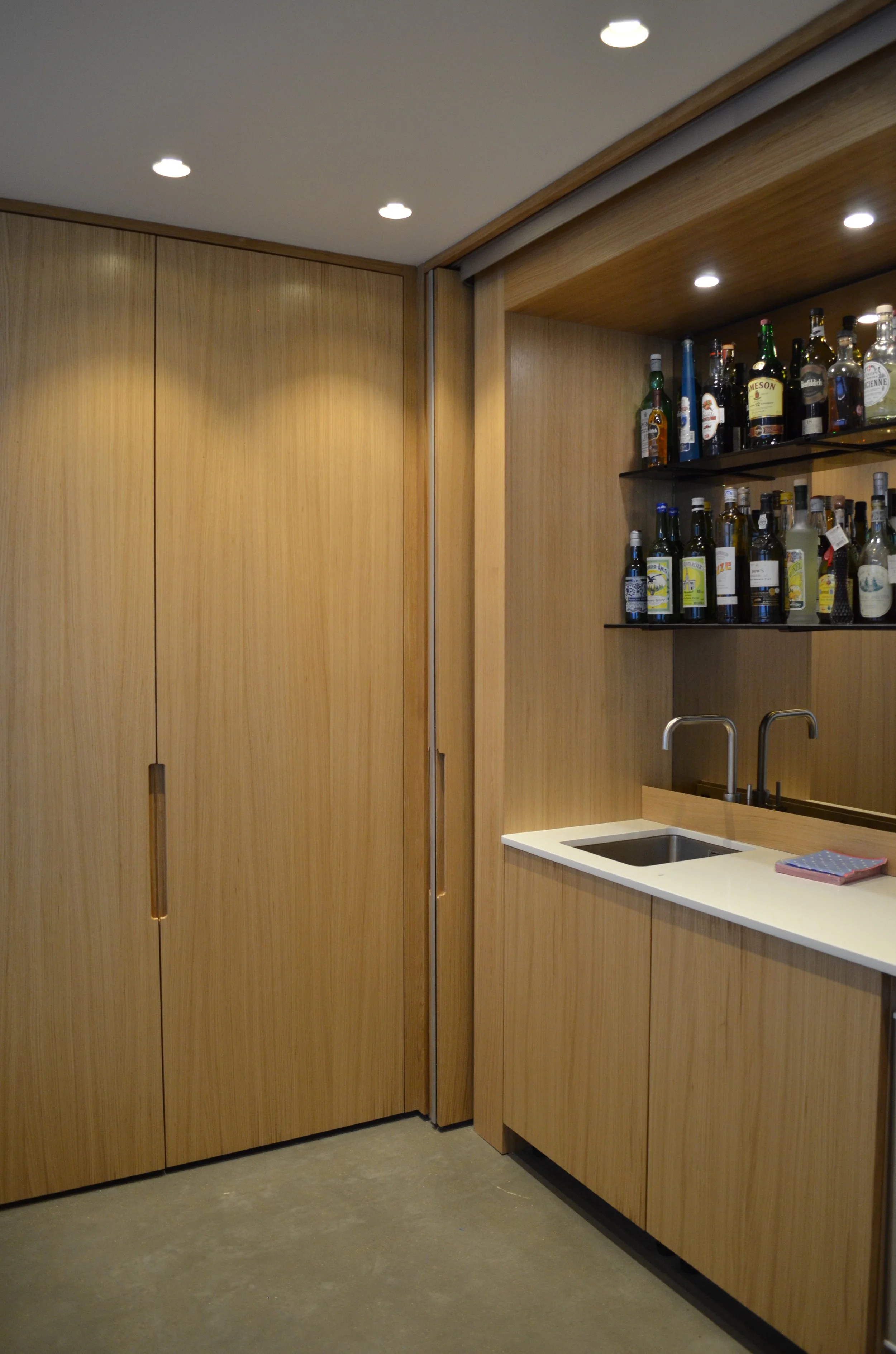 Wooden cabinetry and shelves behind bi-fold slide and hide doors