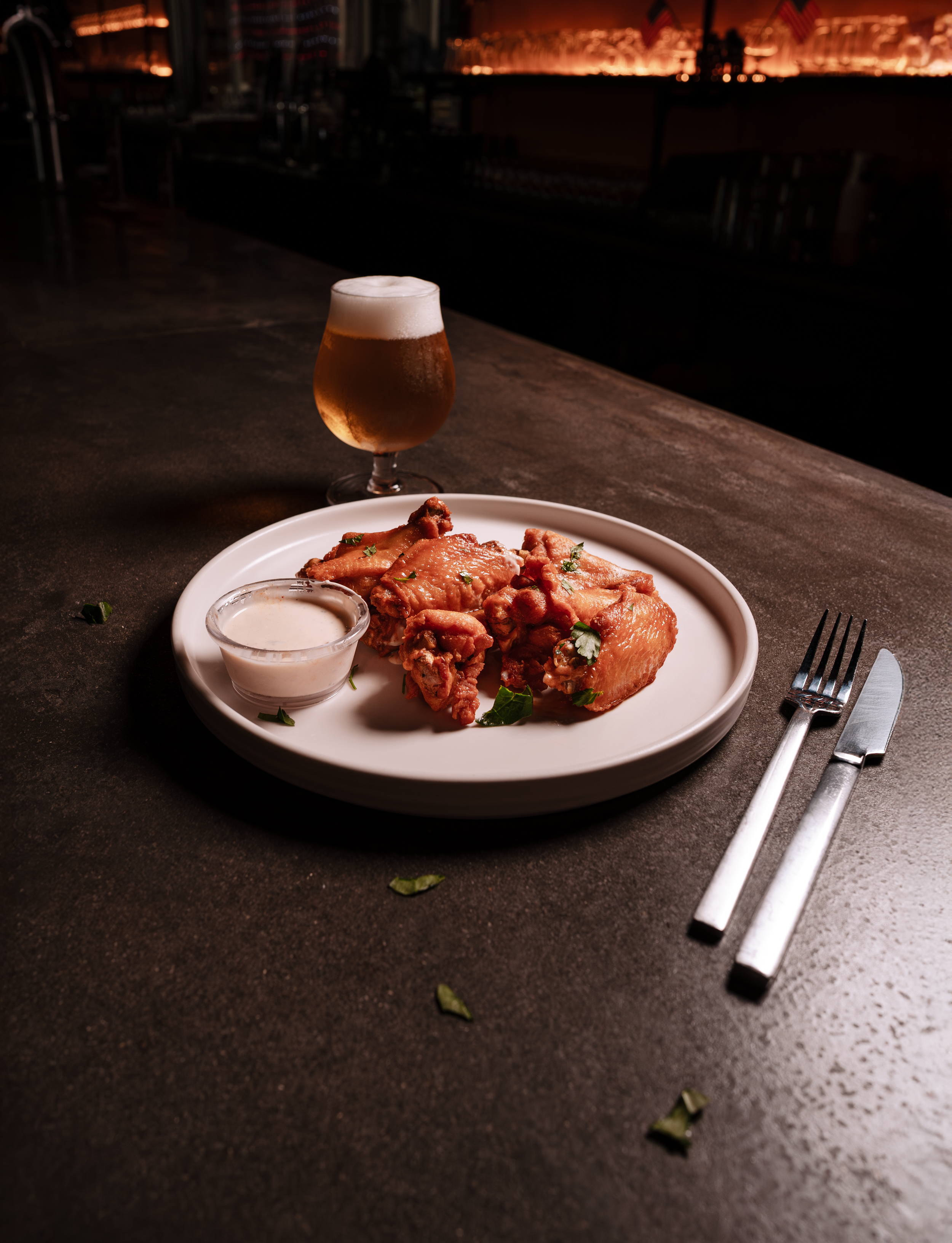 Plate of chicken wings with ranch dipping sauce and a beer