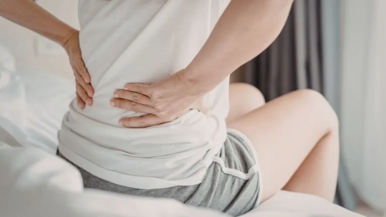 Person experiencing lower back pain, a common symptom associated with spinal conditions such as tethered cord syndrome