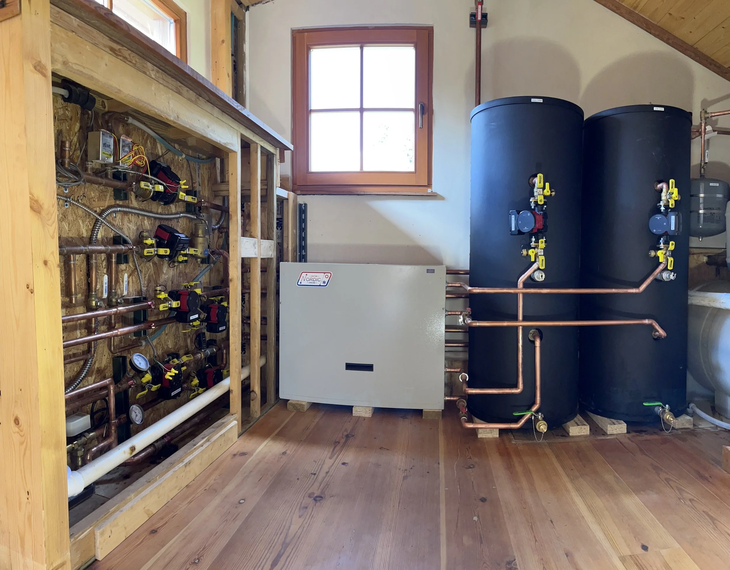 Room with water tanks, pipes, and plumbing equipment for a heating or water system.
