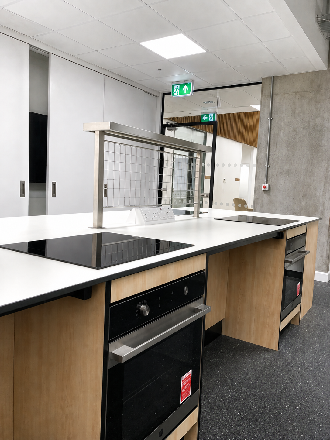 Food technology classroom at Peebles High School featuring fitted timber kitchen units, white worktops, induction hobs and integrated ovens.