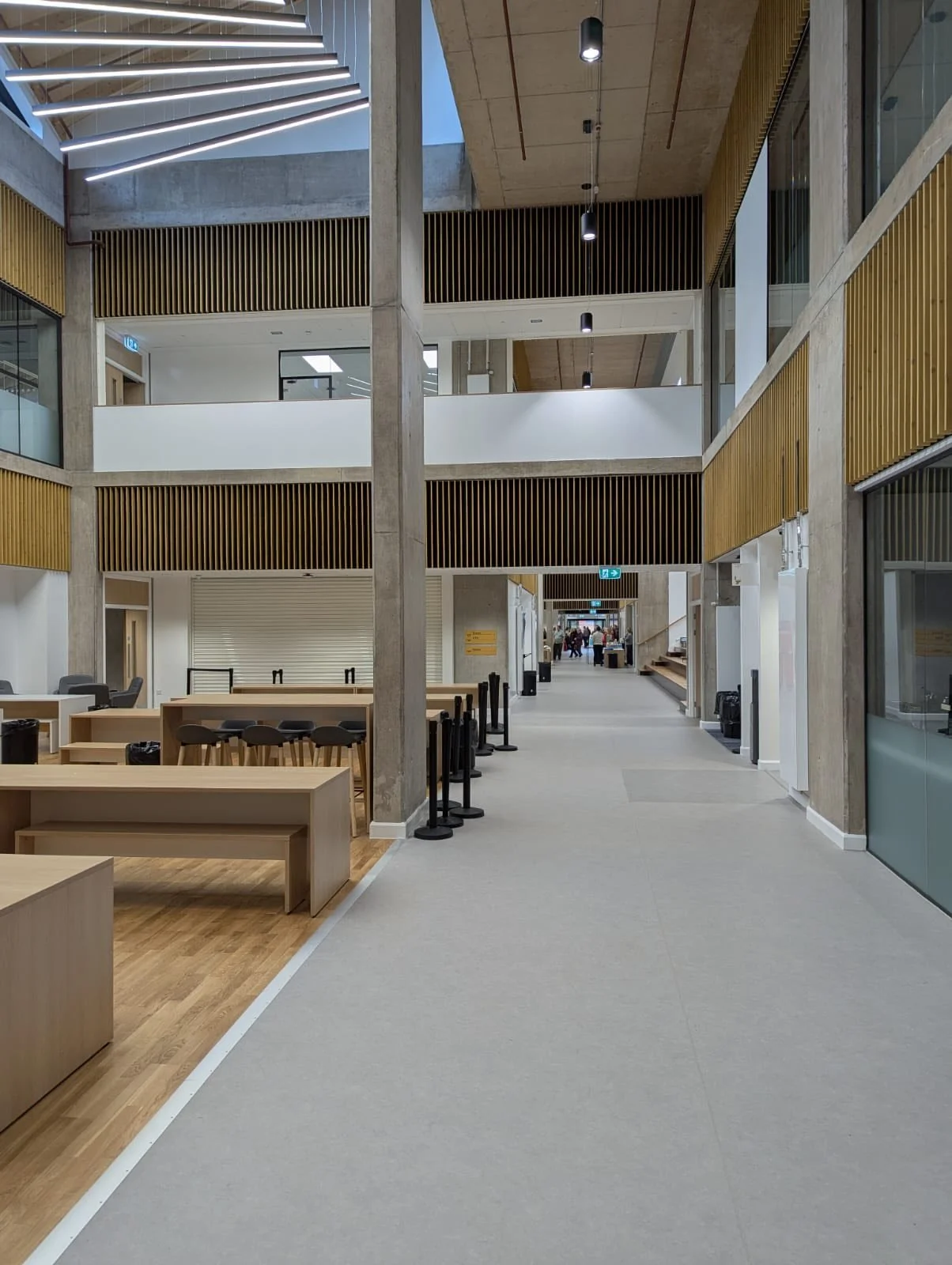 Multi-storey central atrium at Peebles High School featuring timber furniture, informal seating areas, exposed concrete and vertical timber detailing