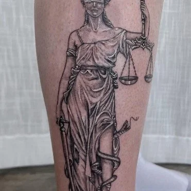 Black and gray stipple shaded tattoo of The Lady Justitia aka Lady Justice as a leg calf tattoo in a realism style