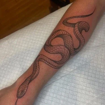 Black and gray tattoo of a snake on a forearm in black realism with stipple shading soft black and gray tones using fine-line tattoo techniques in a feminine motif 
