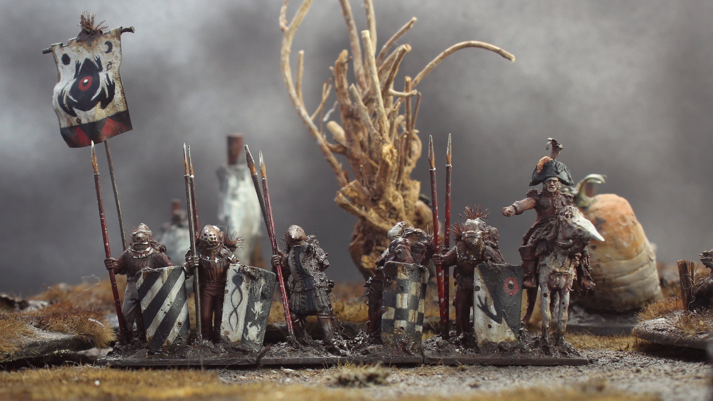 Miniature soldiers in medieval armor with shields and spears, some riding horses, arranged in a line on a textured surface with a small twisted tree and a large snail shell in the background.