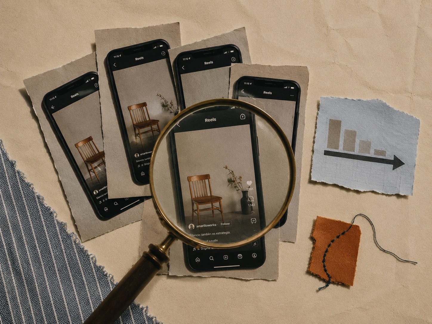 A collection of five smartphones displaying an image of a wooden chair and a vase with branch and flowers on their screens, with a magnifying glass focusing on one phone, a torn piece of paper with a bar graph, a small piece of orange fabric with embroidery, and a piece of torn gray fabric arranged on a beige surface.