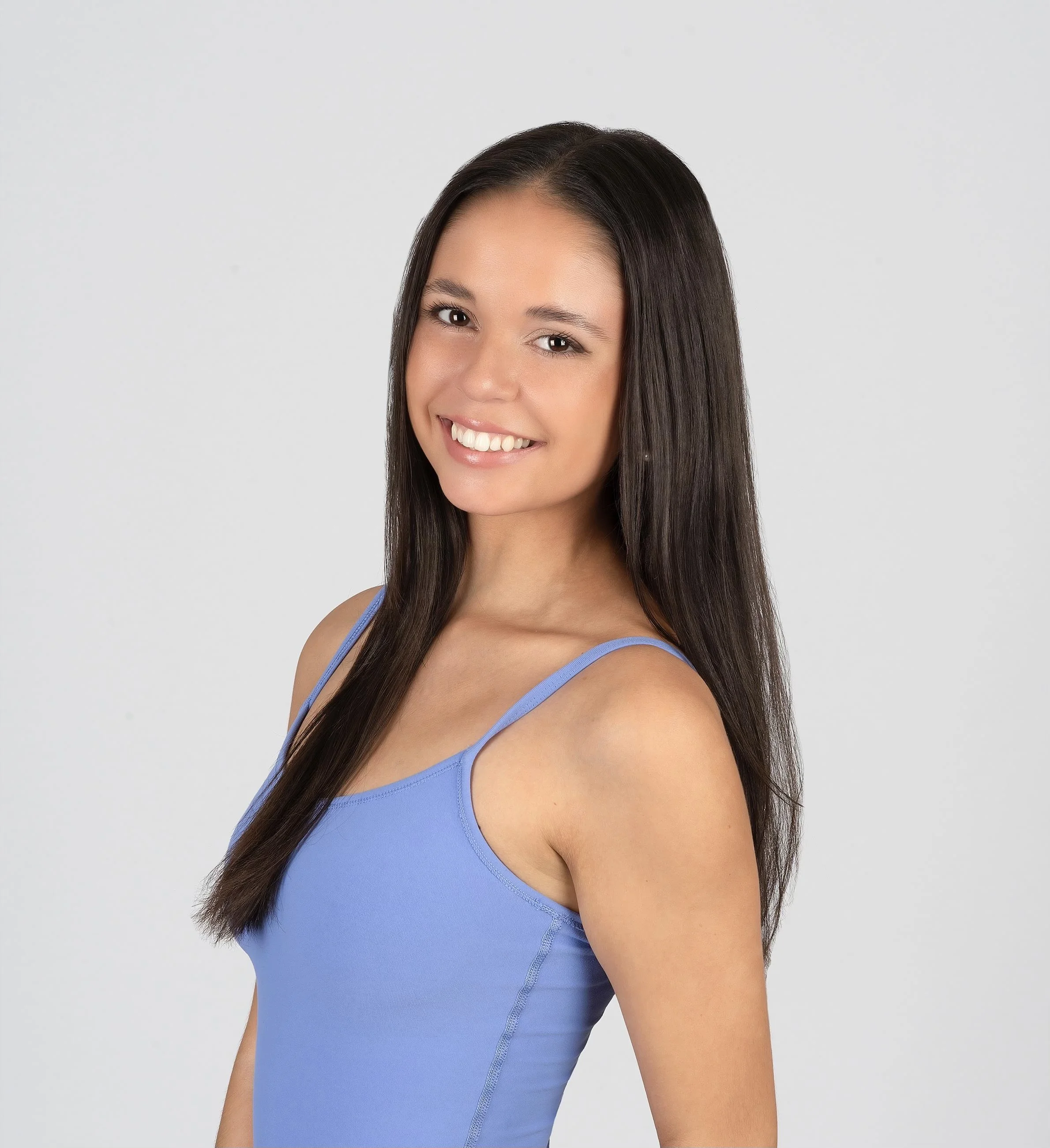 A person practicing yoga on a green mat, in a downward dog pose, with sunlight streaming in.