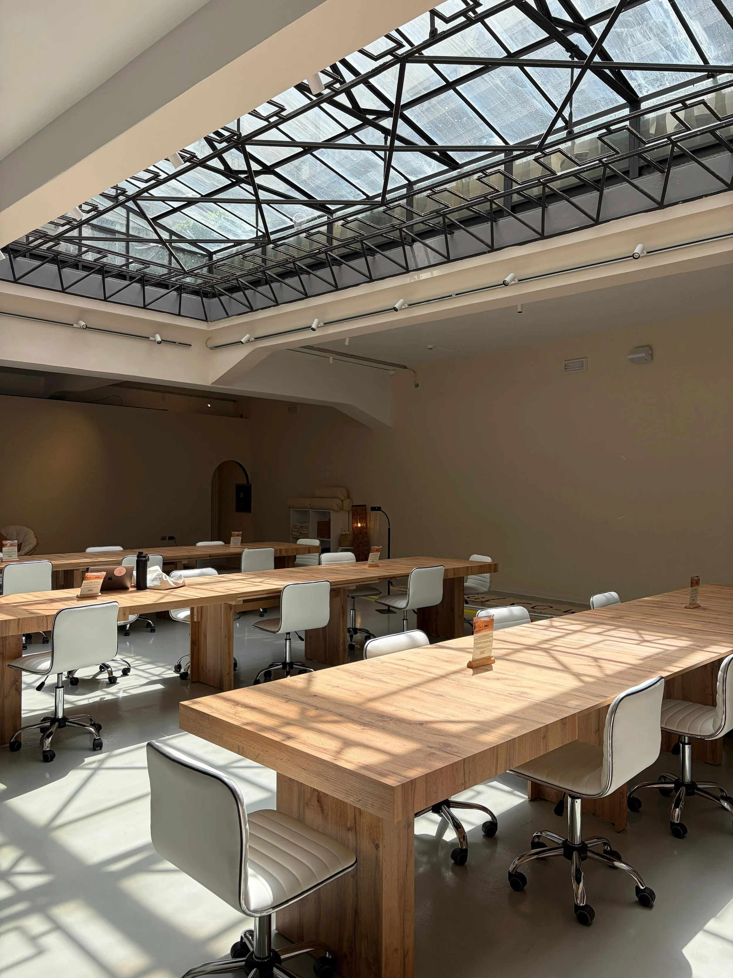 Coworking luminoso con tavoli condivisi e piante a Milano Porta Romana