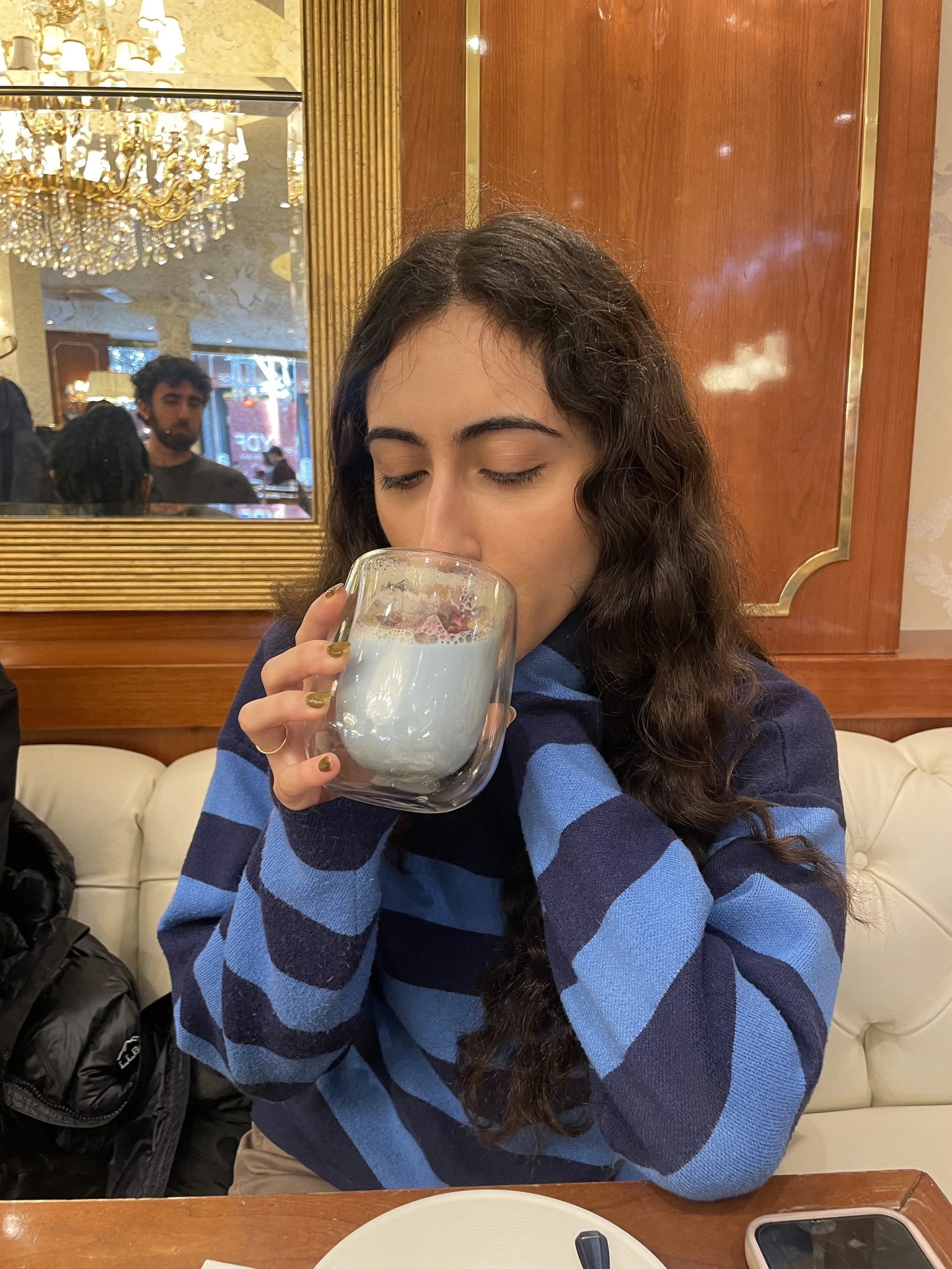 Jenna drinking from a clear mug at a restaurant.