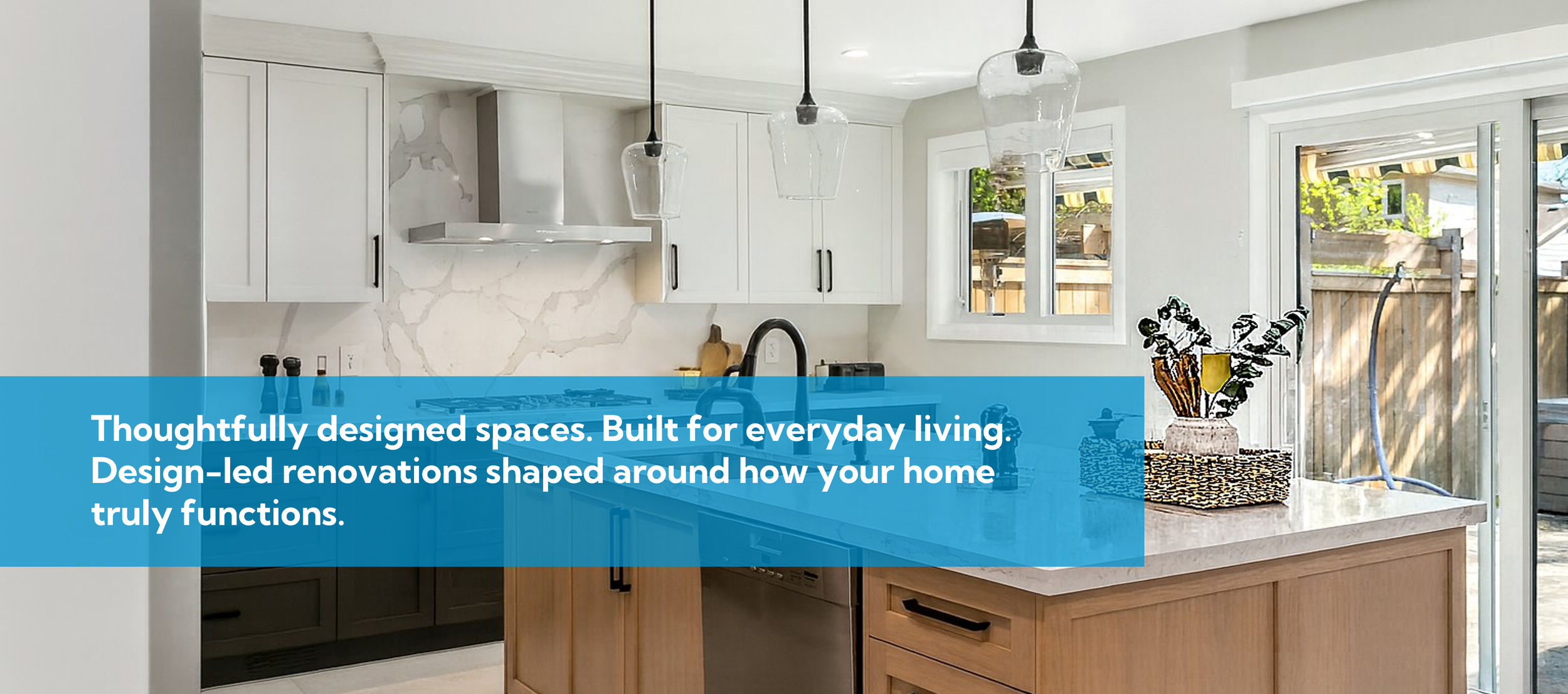 Modern kitchen with white cabinets, marble backsplash, black hardware, pendant lights, and a sliding glass door leading outside.