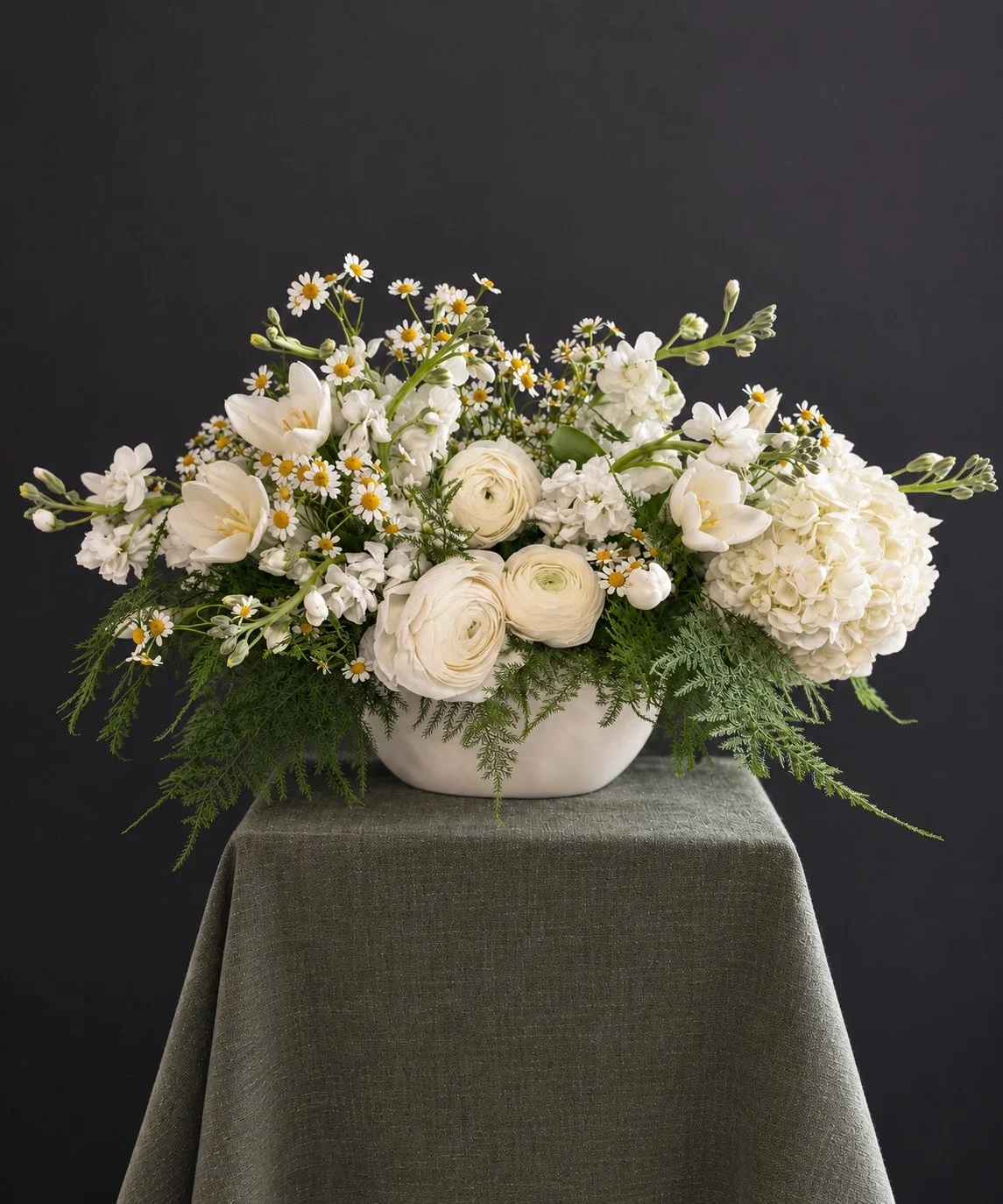 White and green sympathy arrangement with garden flowers and airy foliage in a pale vessel