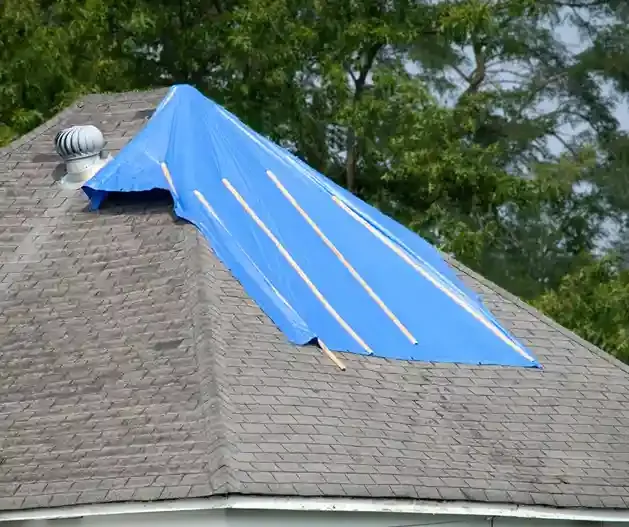Emergency blue tarp secured with wood battens over a damaged asphalt shingle roof in Ocean County, NJ by GRM Roofing