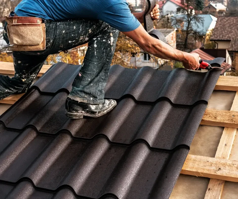 Roofer installing dark metal roof tiles during a roof repair in Ocean County NJ