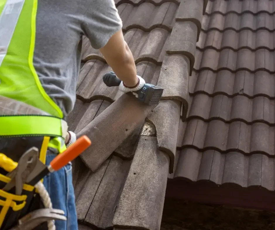 Roofer securing concrete roof tiles with a drill during roof repair in Ocean County NJ