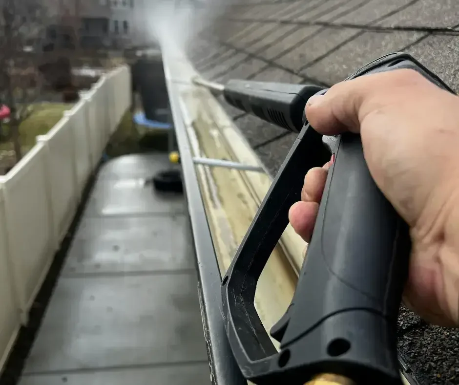 Pressure washing a gutter to flush out debris during gutter cleaning in Ocean County NJ