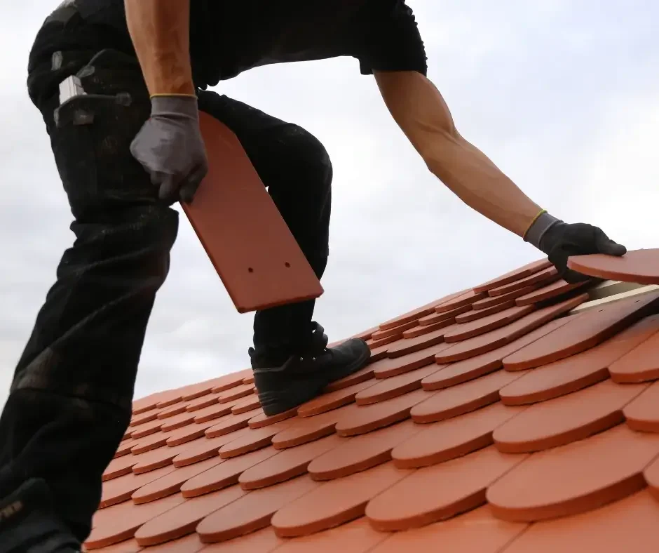 Skilled roofer placing terracotta clay tiles by hand during a roof replacement in Brick Township NJ