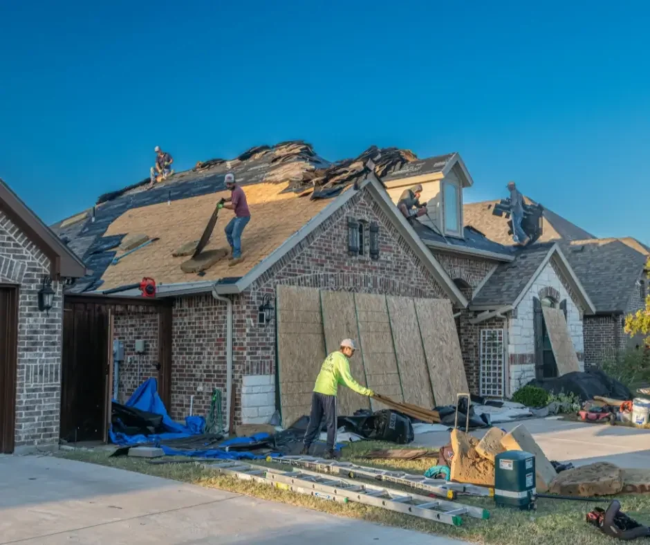 Roofing crew tearing off old shingles and clearing debris during a full roof replacement on a Long Beach Island home
