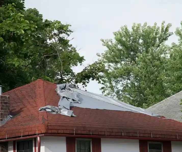 Residential roof with storm damage covered by an emergency tarp in Ocean County, NJ serviced by GRM Roofing