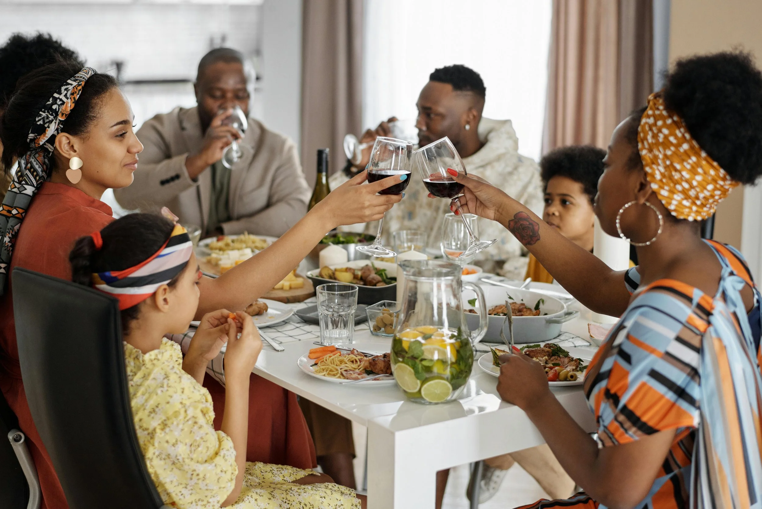 A diverse family sharing a meal at a dinner table, clinking glasses of red wine in a toast.