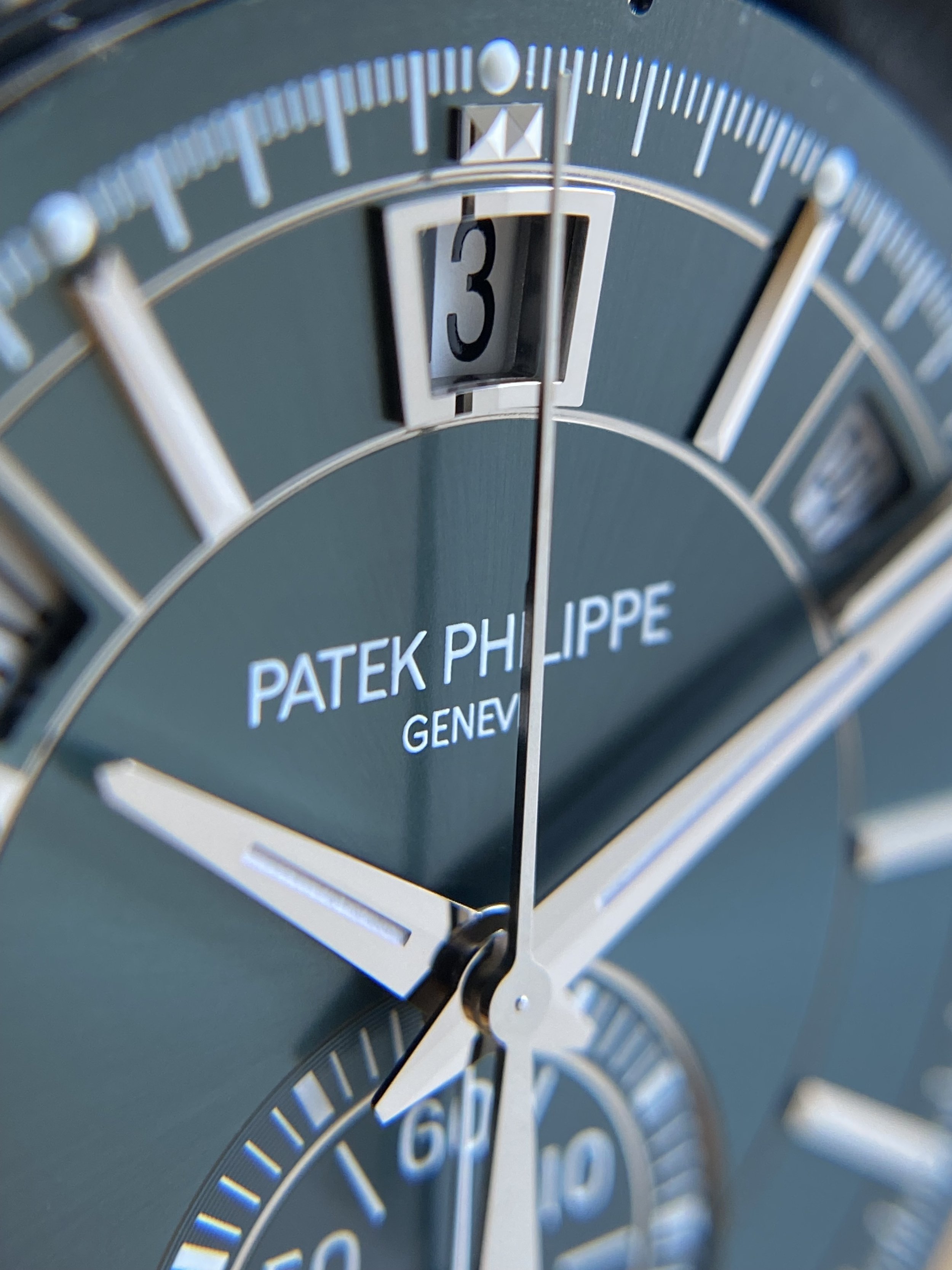Close-up of a luxury Patek Philippe watch face showing the date, minute, and second hands, with the brand name "Patek Philippe Geneva" on the dial.