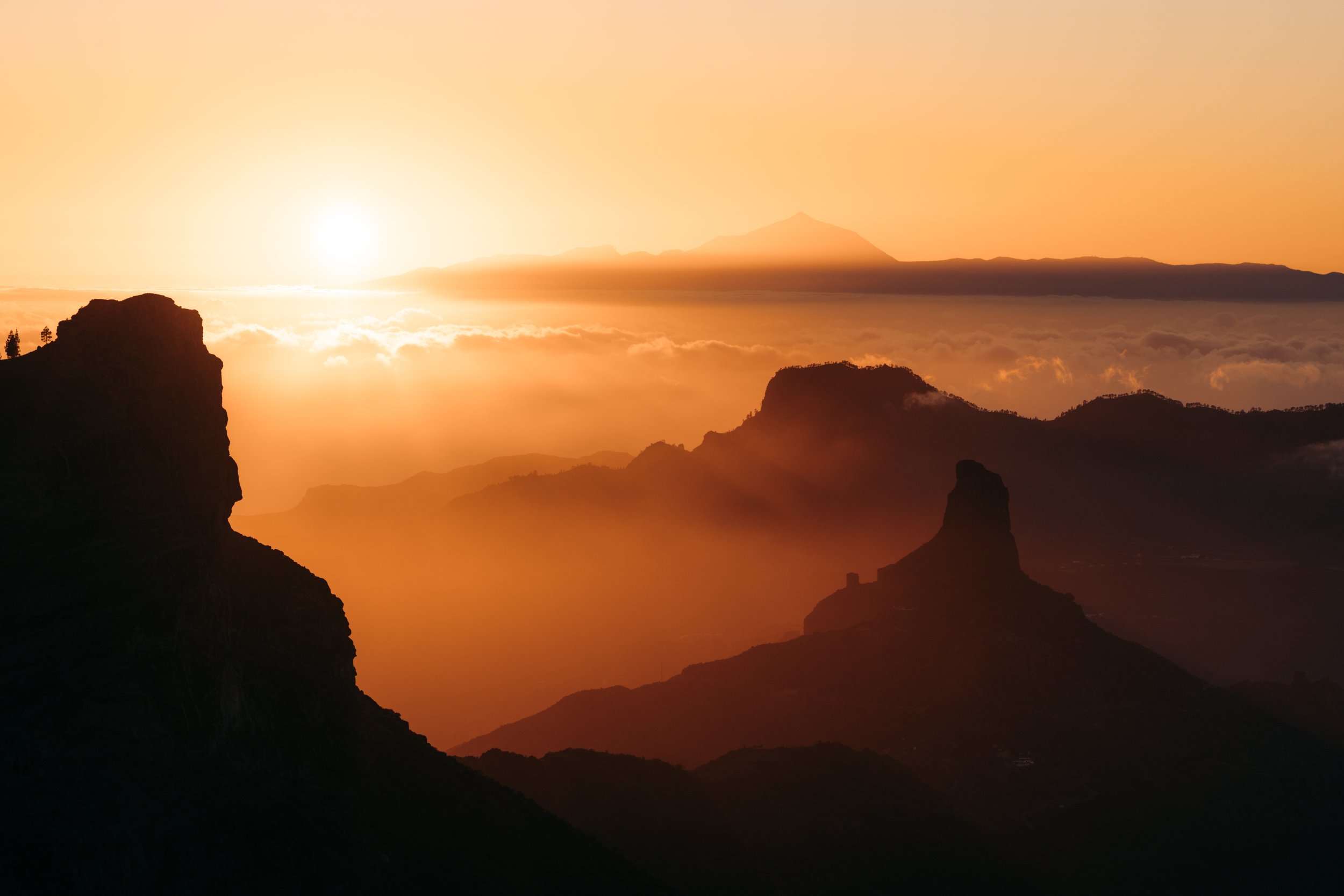 Amanecer sobre montañas con siluetas y niebla