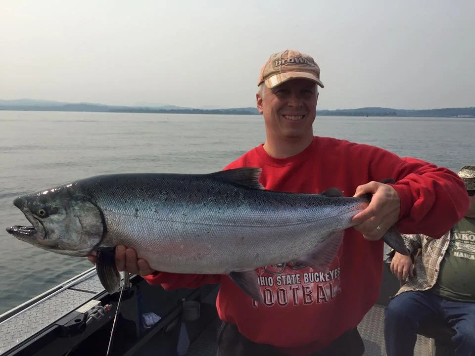 fisherman holding up silver chinook salmon caught with fishing charter in Oregon