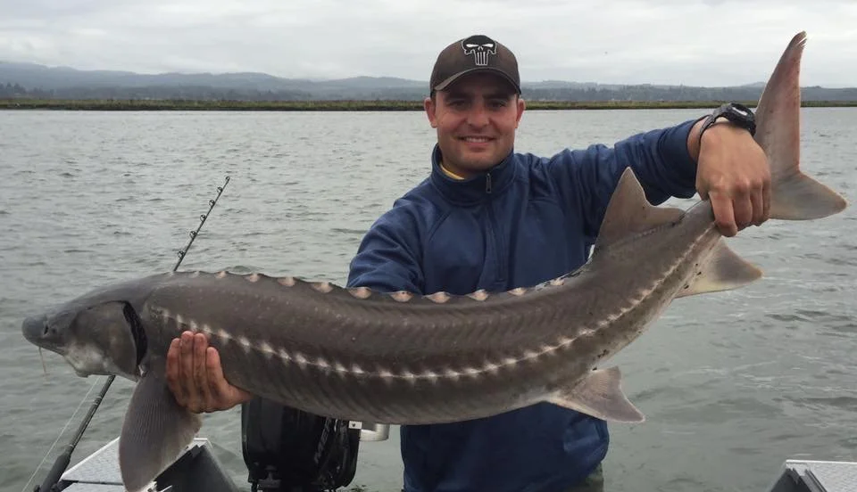 fisherman holding up sturgeon caught with fishing charter in Oregon