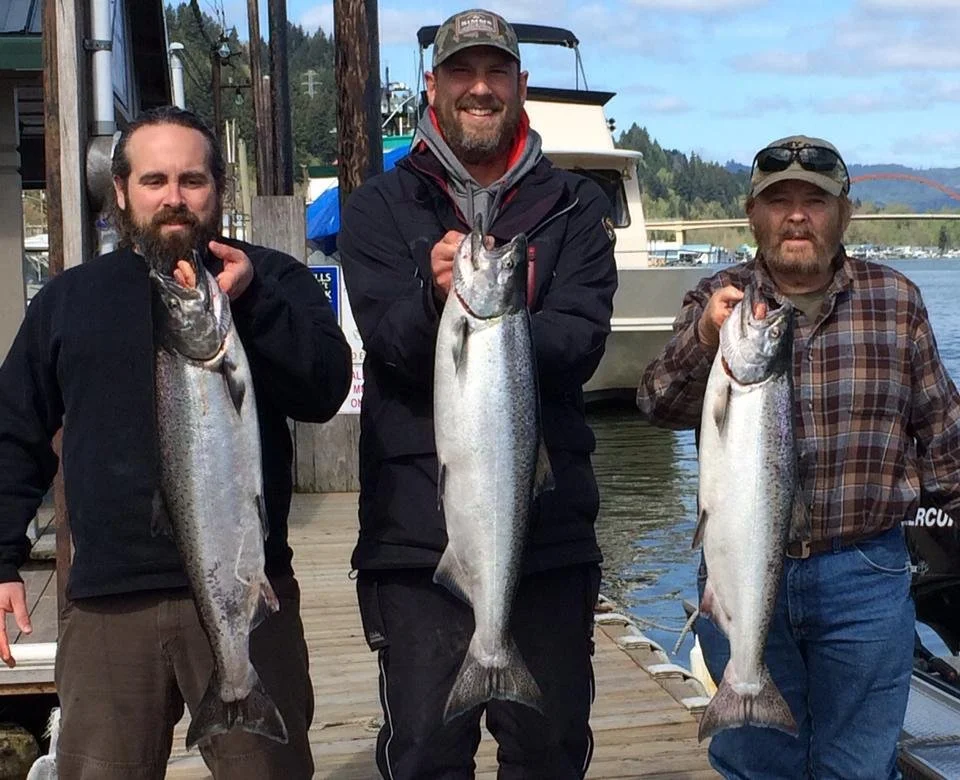 fishermen holding up silver chinook salmon caught with fishing charter in Oregon