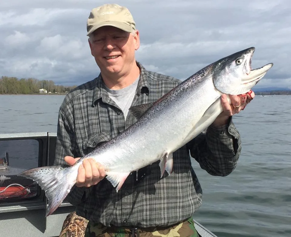 fisherman holding up silver chinook salmon caught with fishing charter in Oregon