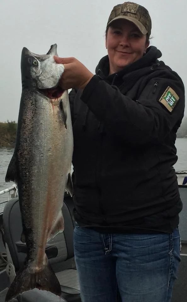 woman holding up silver chinook salmon caught with fishing charter in Oregon