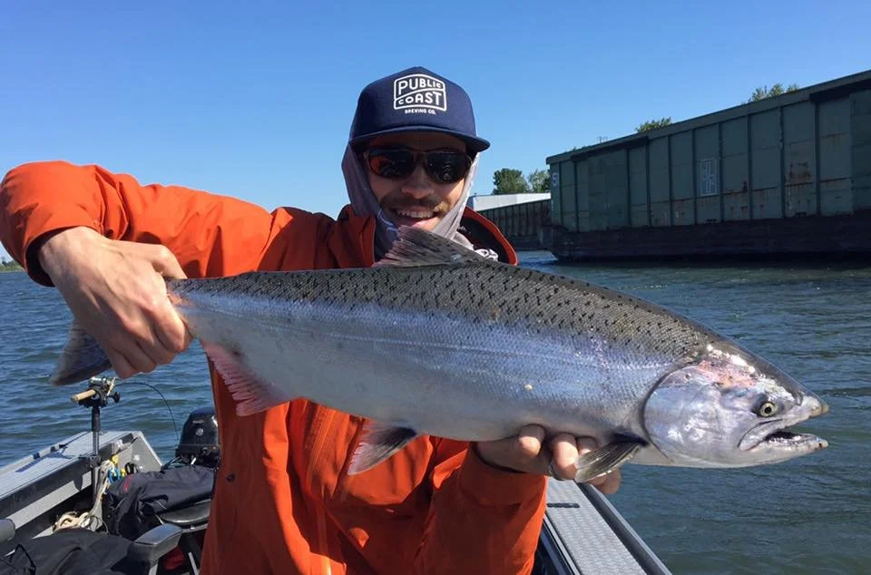 fisherman holding up silver chinook salmon caught with fishing charter in Oregon